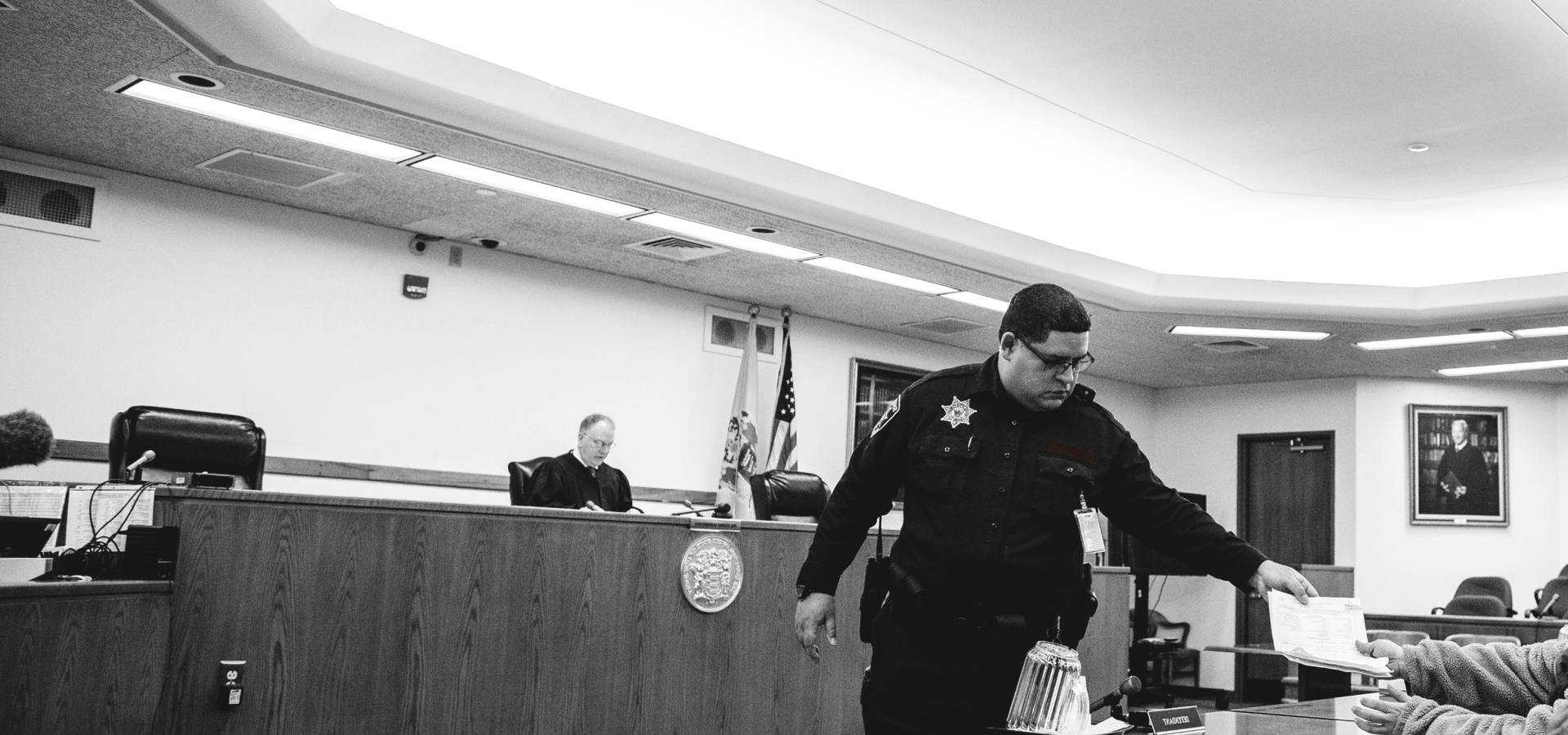 a court room official handing a document to a defendant